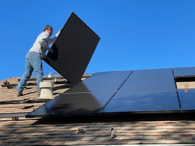 solar panel replacement; a person installing solar panels on the roof