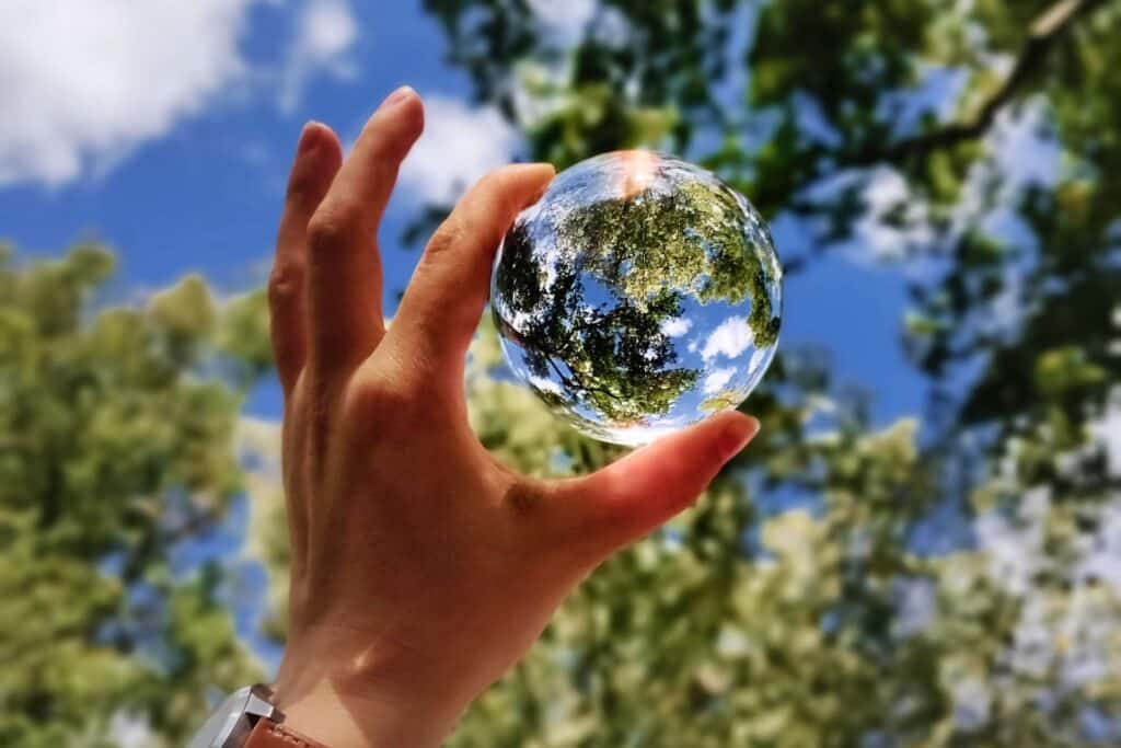 green initiatives; a man holding a transparent globe in the forest.